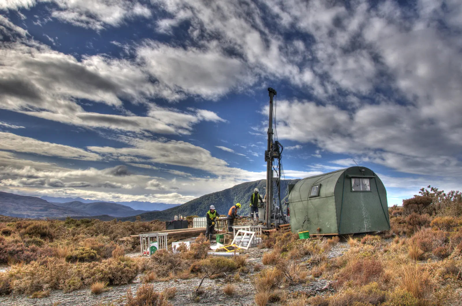Exploration drilling crew operating a drill rig in remote South Island terrain