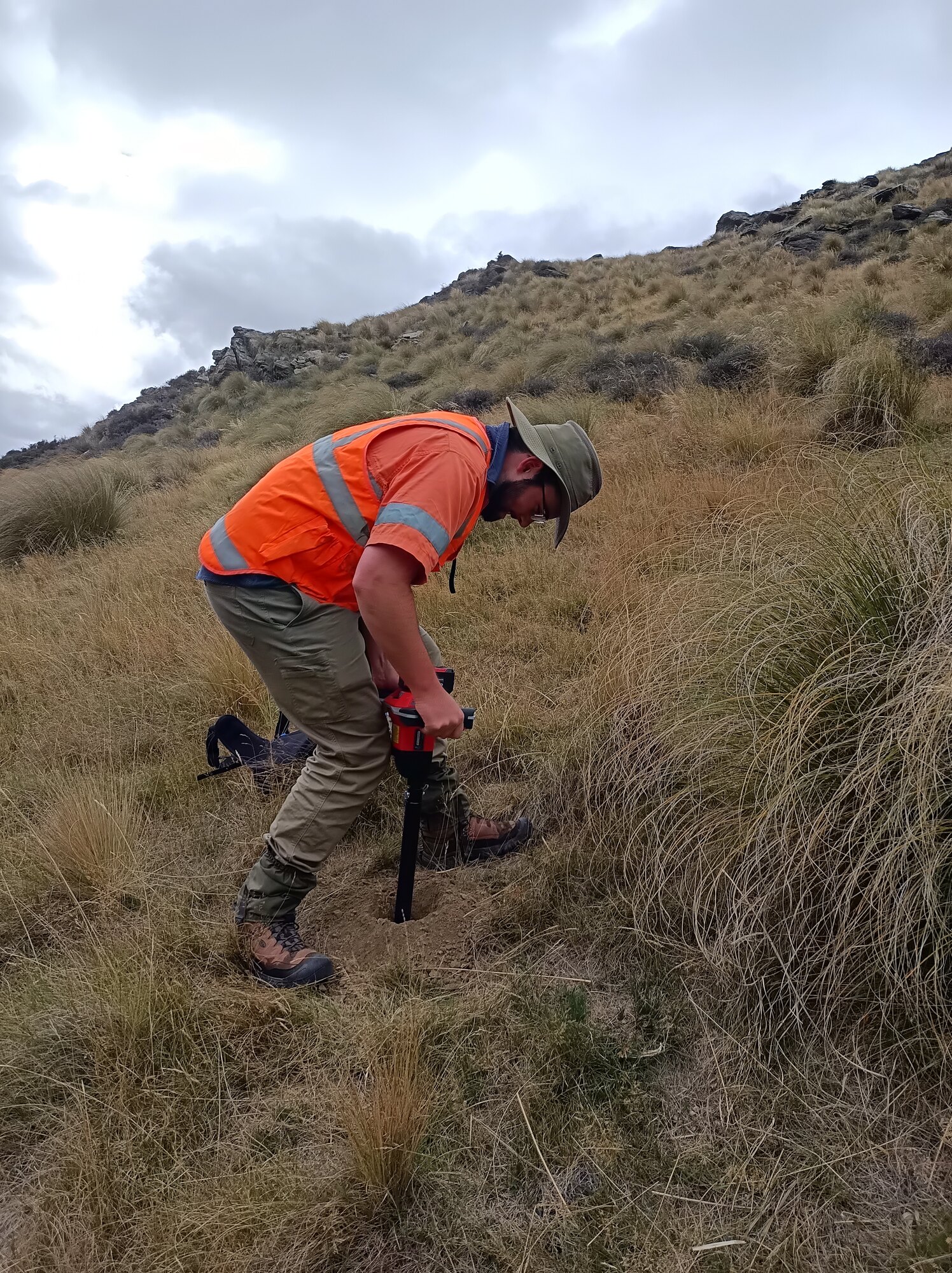 Geologist collecting a soil sample in Otago tussock country
