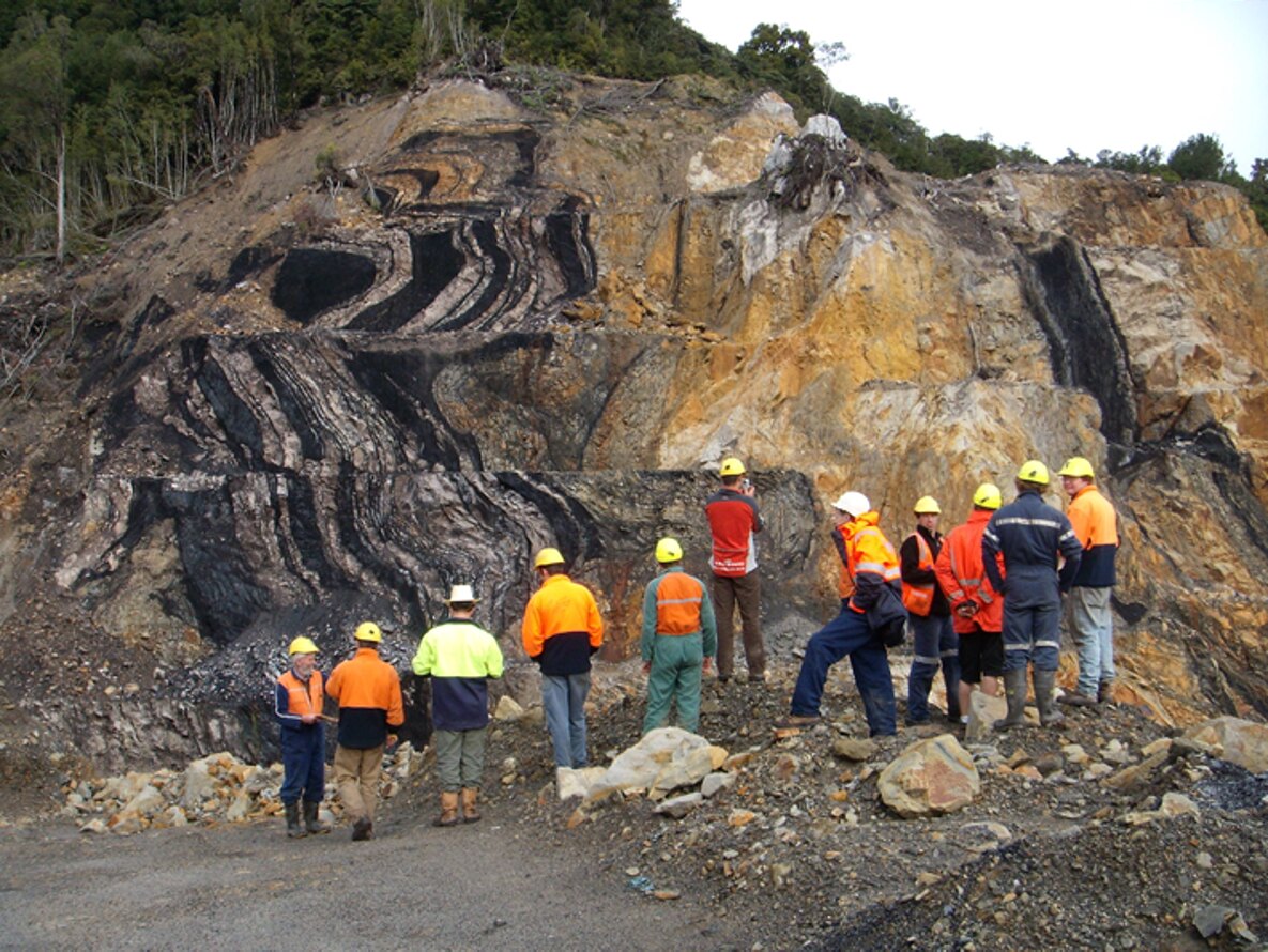 Field team inspecting folded coal seams in an exposed highwall